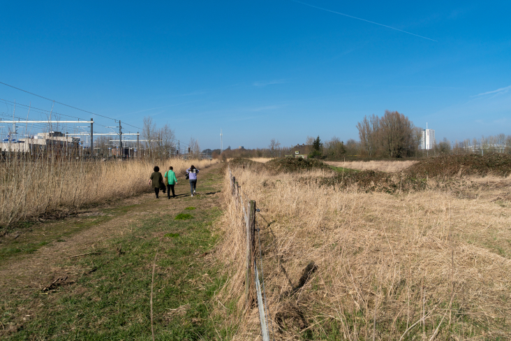 mensen lopen langs het spoor op weg naar hun opvangplek