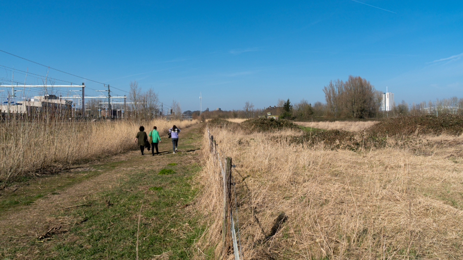 mensen lopen langs het spoor op weg naar hun opvangplek
