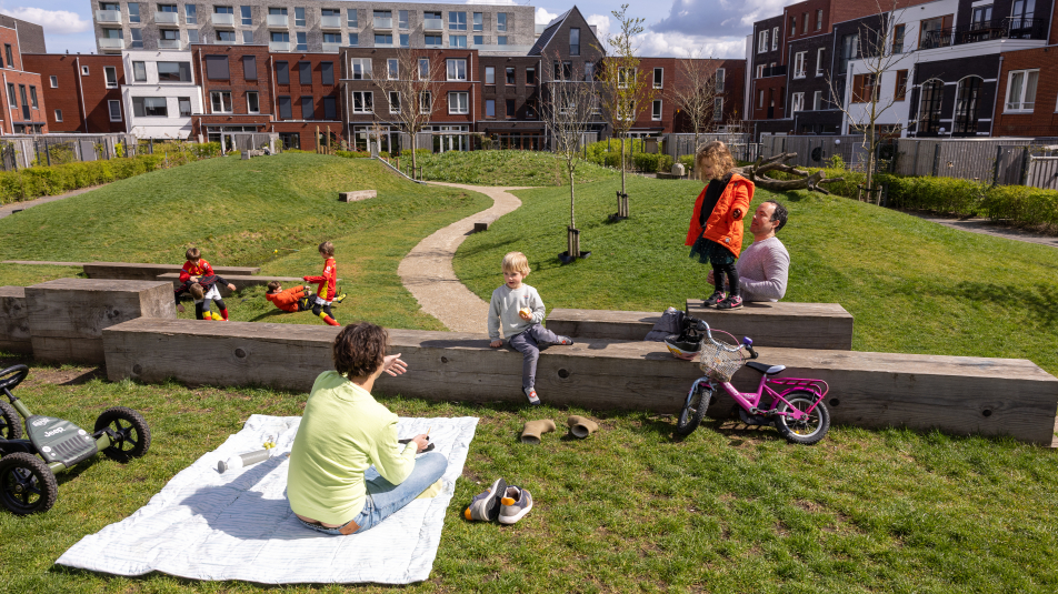 ouders en kinderen op een grasveldje in een nieuwbouwwijk